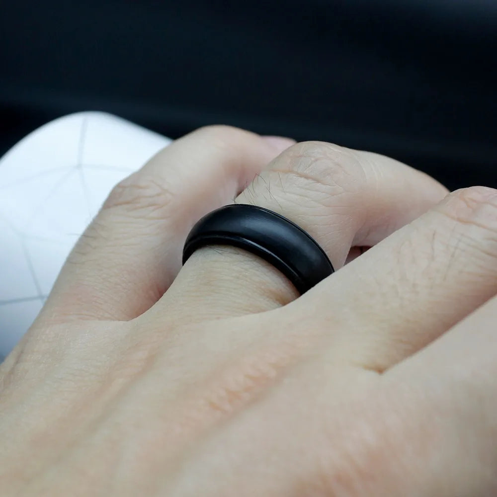 Hand wearing a black ring with a blurred background