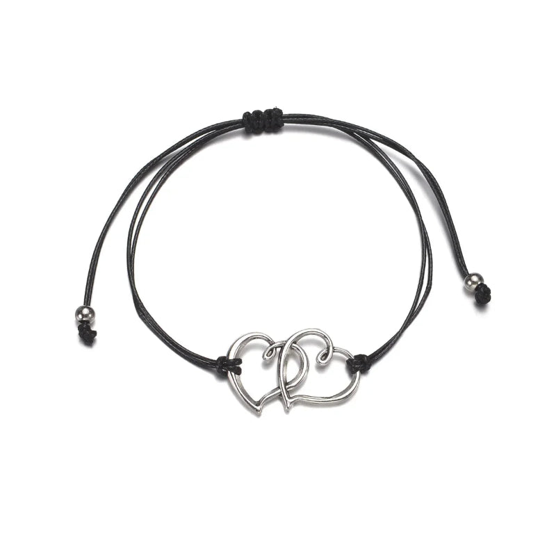 Black cord bracelet with a silver interlocked hearts charm on a white background