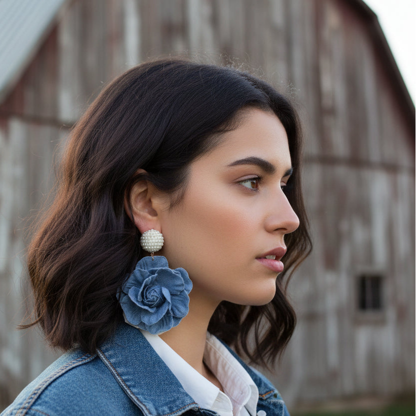 Woman wearing blue floral earrings with a rustic background