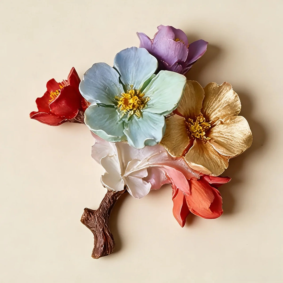 A decorative floral arrangement on a branch with multiple sculpted flowers in pastel blue, lavender, red, peach, cream, and metallic gold tones, photographed on a plain warm beige background, made with a silicone mold.