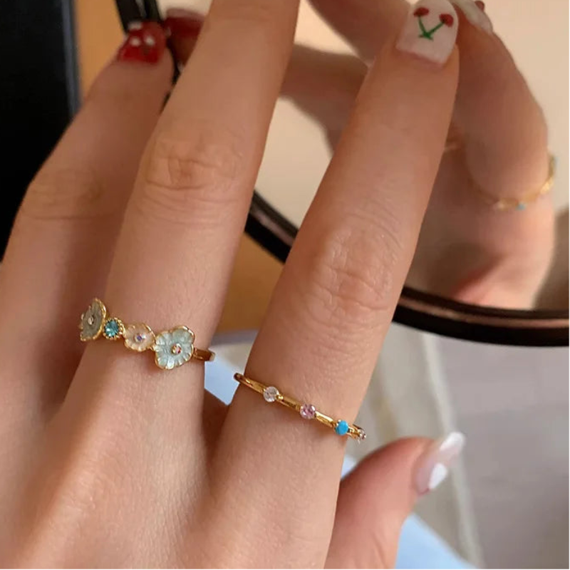 Close-up of a hand wearing two rings with gemstones in front of a mirror.