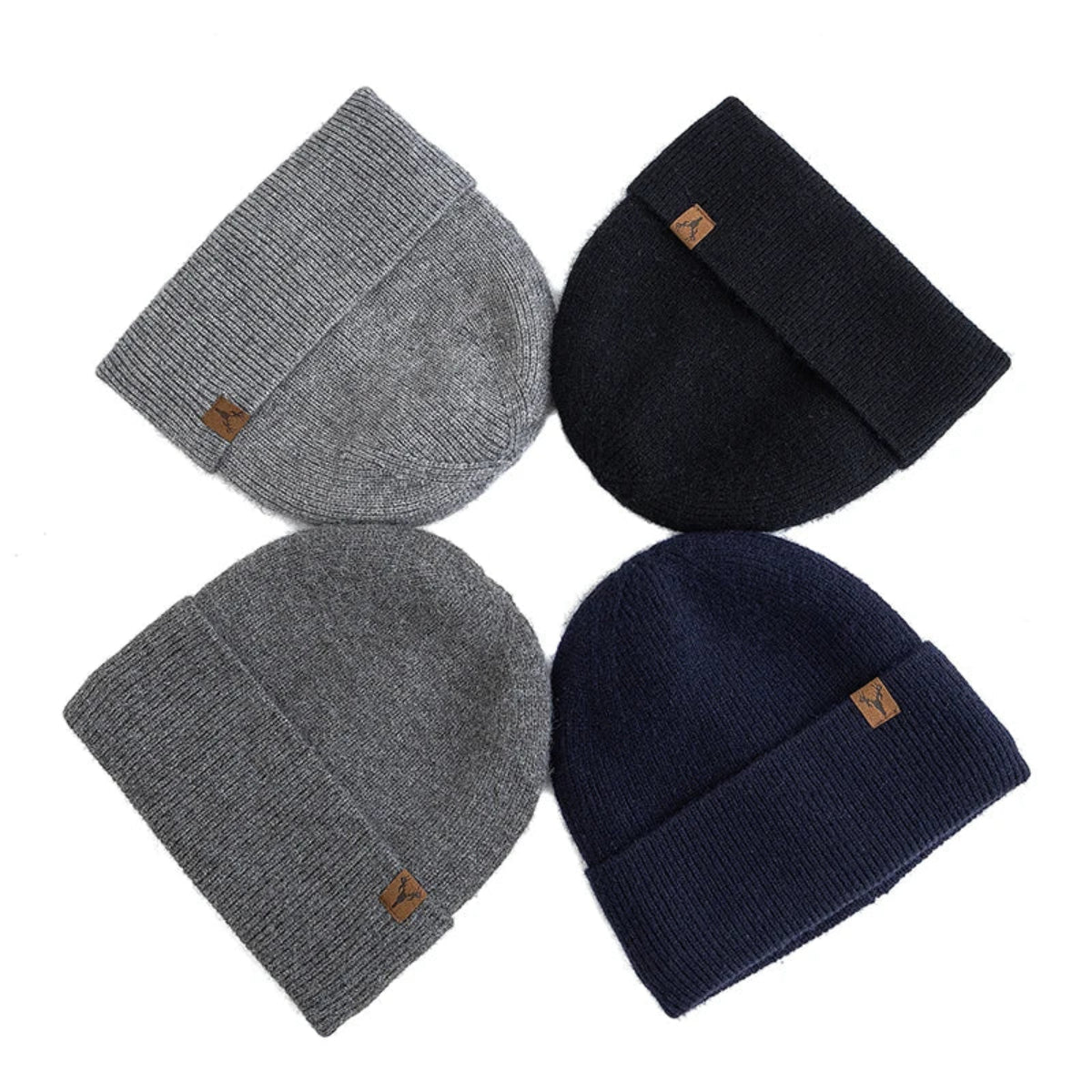 Four beanies in gray, black, and navy with brown tags on a white background