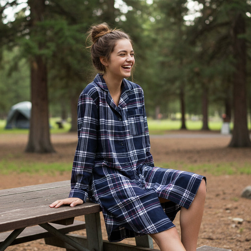 Woman wearing a blue plaid robe sitting on a wooden bench in a park.