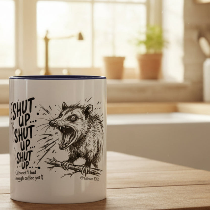 A white ceramic mug with a black illustration of a panicked possum sits on a wooden kitchen island, with a softly blurred modern kitchen in the background.