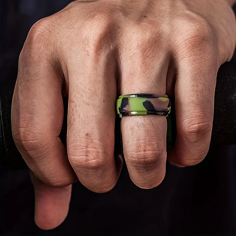 Hand wearing a green camouflage ring on a dark background