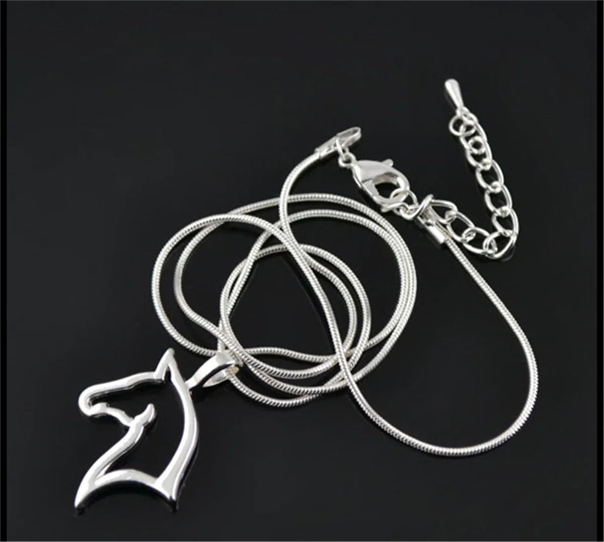 Silver necklace with a horse head pendant on a black background