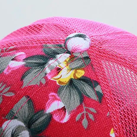 Top side button detail on a Pink floral cap with mesh back on a light gray background.