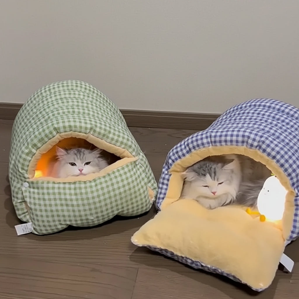 Two checkered pet beds with cats inside, one green and one blue and yellow, on a wooden floor.