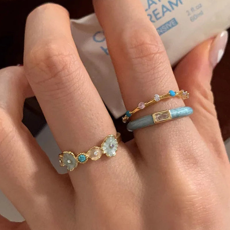 Hand wearing multiple rings with a blurred background