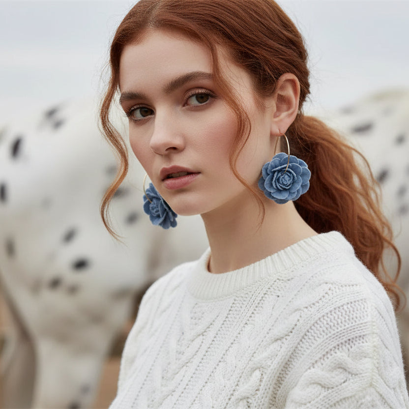 Woman wearing blue floral earrings with a blurred background