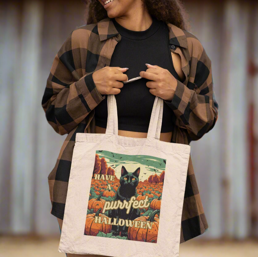a woman in a flannel shirt holding up a black cat Halloween tote bag