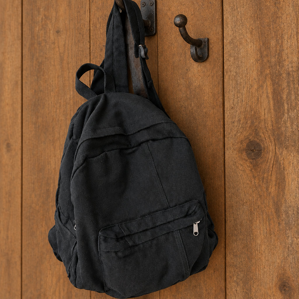 Black backpack hanging from a rack in a barn