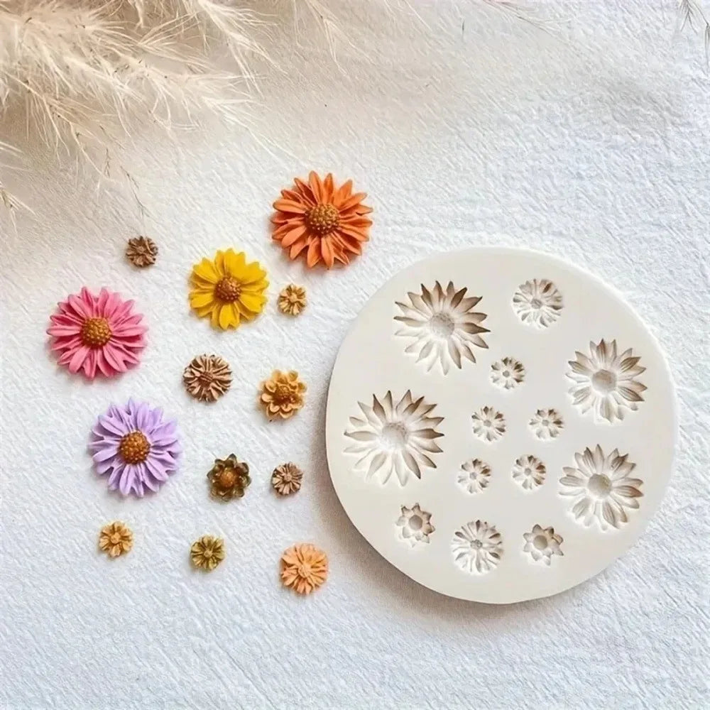 A round white silicone mold with floral petal cutouts, displayed next to various small dried flowers in pink, yellow, orange, and purple on a textured white fabric background.