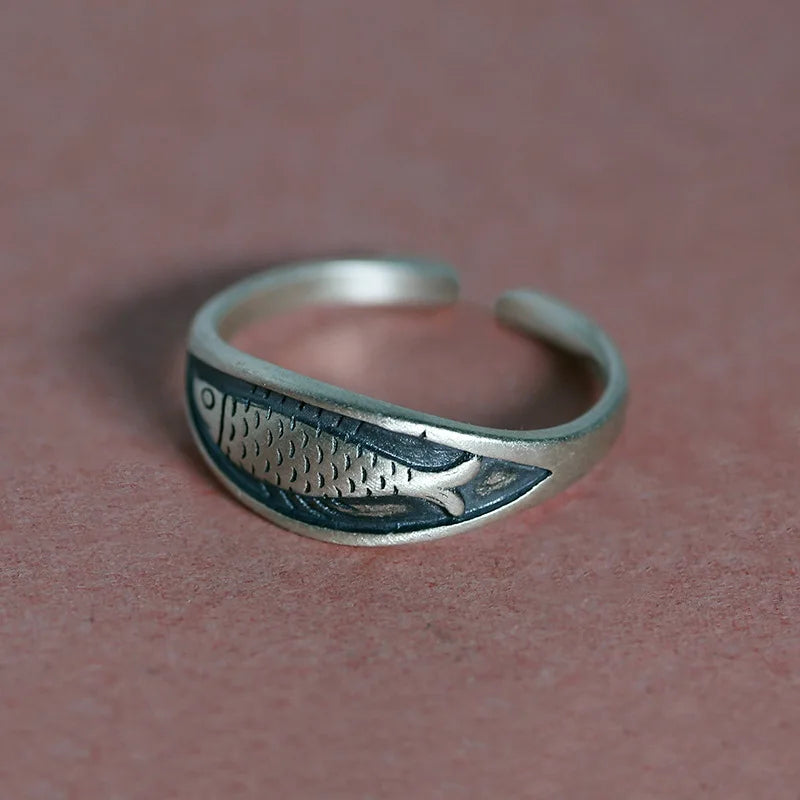 Silver ring with fish design on a brown background