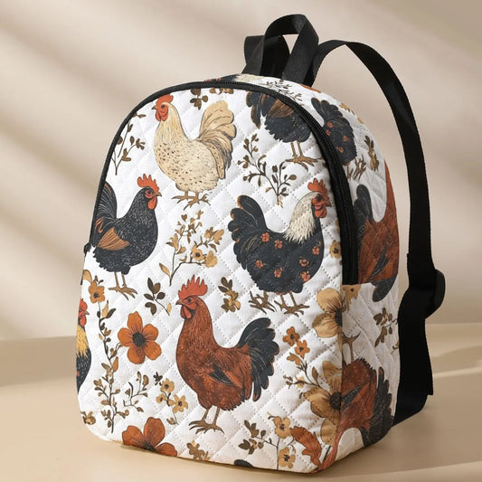 A quilted backpack featuring a vintage-style print of various chickens and floral motifs on a white background, with black straps and trim, set against a warm beige background with soft diagonal shadows.